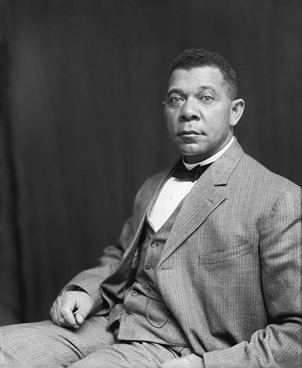 A portrait of a seated man wearing a three-piece suit and a bowtie. He stares intently at the camera.