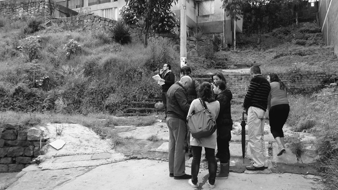 Figure 6.3. Several people stand outside at the base of a hill, with some buildings in the background.