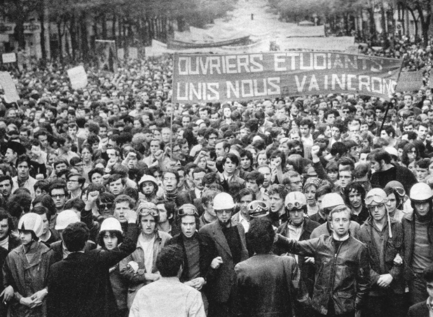 Figure 17. A boulevard is completely filled with thousands of marching students carrying banners stretching back as far as the camera can capture. The first banner reads “Ouvriers Etudiants Unis Nous Vaincrone” (Workers Students United We Will Win).